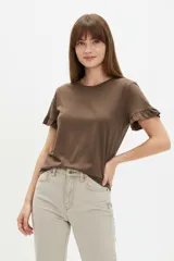 Remera blanca de algodón, de corte ajustado, con cuello redondo y mangas cortas terminadas con volados delicados.