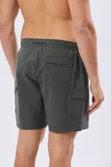 Short de baño cargo color negro, de diseño liso con bolsillos laterales y bolsillos utilitarios con solapa y botón en las piernas. Cuenta con cintura elástica ajustable mediante cordón.