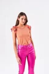 Top color salmón metalizado, de algodón peinado, con cuello redondo y mangas cortas con volados con borde fucsia.