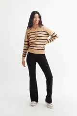 Sweater de punto color crema con rayas horizontales azul marino, cuello redondo y media botonadura frontal con botones marrones.