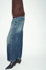 Jeans de tiro bajo, corte recto y largo completo (full length), color azul medio con efecto desgastado y lavado. Modelo de cinco bolsillos con cierre frontal de botones.