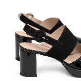 Zapatos de taco alto y plataforma delantera con diseño destalonado. Combinan una puntera cerrada de charol negro con una tira ancha de gamuza sobre el empeine y tira ajustable con hebilla en el talón.