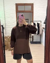 Buzo de punto color marrón, con cuello redondo, mangas largas con puños ajustados y diseño holgado.