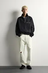 Sudadera de corte relajado confeccionada en denim de algodón con efecto lavado. Presenta cuello subido con cierre frontal de cremallera, manga larga con puños elásticos y bajo elástico. Incluye un bolsillo con cierre de cremallera en el pecho.