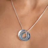 Collar con dije compuesto por tres aros entrelazados de plata 925, con cadena de eslabones tipo veneciana.