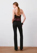 Jeans negros de tiro alto y estilo flare, con diseño largo, cinco bolsillos y cierre frontal de cremallera y botón.