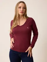 Remera de manga larga color bordó, con cuello en V y logo de pájaro bordado en el pecho.