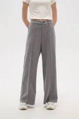 Pantalon de corte holgado y tiro alto, confeccionado en tejido de punto gris con costuras frontales verticales que simulan una tabla.