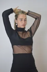 Vestido corto negro con cuello alto, mangas largas de tul y transparencias en el torso y abdomen.