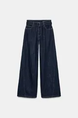 Jeans de tiro alto con pierna ancha, confeccionados en denim azul oscuro. Presentan cinco bolsillos, trabillas en la cintura y un cinturón ajustable del mismo tejido con hebilla metálica. Incluyen pespuntes marcados a tono y cierre frontal con cremallera y botón.