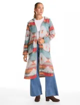 Cardigan largo con capucha, confeccionado en tejido estampado con diseño geométrico en tonos tierra, verde y rojo. Presenta frente abierto, mangas largas y bolsillos laterales.