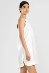 Vestido corto blanco de lino italiano con fibra metalizada, corte holgado y sisas amplias. Presenta cortes redondeados a los costados y la insignia de tigre Polonio en la espalda.