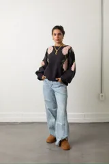 Buzo de punto color negro con estampado floral en tonos rosado y verde. Presenta cuello redondo, mangas largas con diseño abullonado y corte holgado.