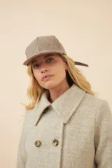 Gorra con visera confeccionada en lana fina sin teñir, con un sutil patrón de tejido en espiga.