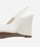 Zapato blanco de punta fina con taco alto tipo anabela (cuña) y tira elástica tipo slingback en el talón.