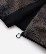 Campera de sherpa con estampado camuflado en tonos marrones y grises, de corte oversize y manga larga. Presenta cuello alto, cierre frontal completo y un bolsillo frontal contrastante en color negro con cierre.