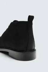 Bota de caña baja con cordones, confeccionada en piel con acabado abatanado. Presenta horma redonda y suela con ligero tacón.