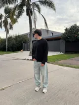Sweater de punto con diseño bicolor y texturas combinadas, presenta un lado de tejido liso y otro con trenzado vertical. Posee cuello redondo, corte holgado y una etiqueta decorativa en el frente.