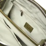 Cartera tipo tote de tamaño pequeño en color verde oliva, confeccionada en material textil. Presenta doble asa de mano, correa de hombro ajustable y un detalle decorativo de borla con cordones en el frente. Incluye un aplique circular con el logo de la marca en la parte inferior.