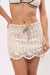 Minifalda color crema tejida a crochet con cintura con cordón ajustable.