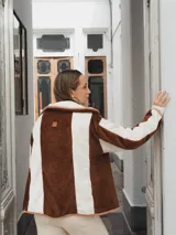 Campera con capucha, de tela tipo peluche a rayas verticales color marrón y blanco, con ribete color beige.