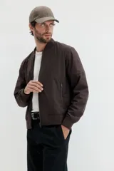 Campera bomber de color marrón oscuro, con cuello, puños y bajo acanalados. Posee cierre frontal y bolsillos laterales con cierre.