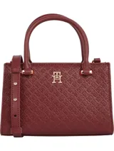 Cartera tote Tommy Hilfiger color borgoña con diseño integral del monograma TH en bajo relieve. Tiene doble asa corta, correa extraíble y ajustable, cierre de cremallera y herrajes dorados.