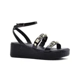 Sandalia de plataforma color negro con tiras finas y apliques de tachas doradas. Cuenta con pulsera al tobillo con hebilla ajustable.