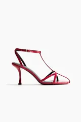 Sandalias rojas de taco fino y alto, con diseño de tiras finas en el empeine, tira en T y pulsera ajustable con hebilla en el tobillo.