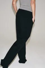 Pantalón de lana negro de tiro medio con trabillas en la cintura, bolsillos laterales ocultos y pierna ancha.