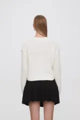 Sweater de punto color celeste, con diseño de trenzas frontales, cuello redondo y corte holgado.