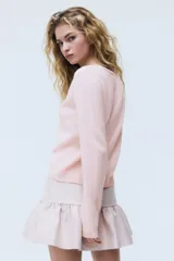 Cardigan de punto suave color rosado, con escote en V, cierre frontal de botones y puños y dobladillo acanalados.