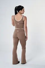 Conjunto deportivo compuesto por un top corto con escote redondo y ribetes blancos, y calzas de tiro alto con detalle de cintura cruzada en color marrón.