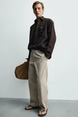 Pantalón relaxed fit para hombre, confeccionado en tejido con mezcla de algodón y lino, en color beige. Presenta bolsillos laterales, bolsillos traseros de plastrón y cierre frontal con cremallera y botón.