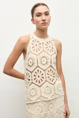 Top halter color beige claro, sin mangas, confeccionado en tejido de crochet con diseño de motivos geométricos y florales calados.