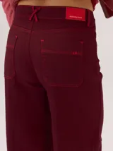 Pantalon de corte ancho y holgado, color verde militar, con diseño de tiro medio, pinzas decorativas debajo de la rodilla, bordado de monograma en el bolsillo delantero y costuras a contratono.