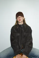 Gorra con visera de pana color marrón, con bordados de corazones rojos distribuidos por toda la superficie. Cuenta con cierre ajustable en la parte posterior.