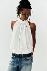 Top halter blanco de diseño fluido con frunces en el cuello, mangas murciélago y bajo con acabado tipo globo.