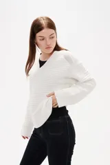 Sweater de punto color blanco, con cuello en V, manga larga y diseño holgado.