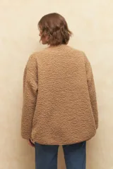 Abrigo gamulán de corderito color crudo, con alamares de cuero sintético negro y cierres metálicos.