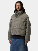 Chaqueta corta tipo bomber con capucha, color verde militar, con cierre frontal de cremallera y botones, bolsillos laterales con solapa y bolsillo utilitario en la manga.