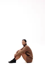 Vestido corto de tejido de punto color marrón, con cuello alto y mangas largas. Presenta un diseño de silueta relajada y terminaciones acanaladas en puños y ruedo.