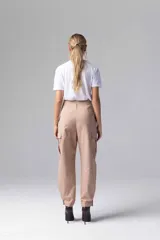 Pantalón gris de tiro alto con pinzas, bolsillos cargo laterales y ruedo ajustable con botones.
