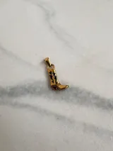 Dije dorado con forma de bota texana con detalles calados en negro, de acero quirúrgico hipoalergénico.