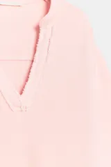 Sudadera de algodón en color rosado, con escote en V y mangas largas de corte holgado.