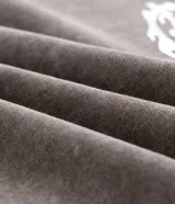 Buzo con capucha de corte boxy, confeccionado en tejido fleece con acabado desteñido. Presenta mangas largas, puños acanalados y una aplicación metálica de un mini icono en el centro del pecho.