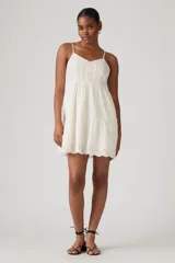 Vestido corto blanco con bordado inglés, breteles finos y falda escalonada.