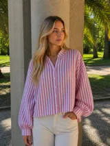 Camisa de lino con diseño a rayas verticales en color rosa y blanco. Presenta un corte oversize, cuello mao, cierre frontal con botones y mangas largas abullonadas con puños ajustados.