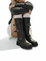 Bota de caña alta confeccionada en cuero, con diseño de estilo biker que presenta tres correas ajustables con hebillas metálicas y suela de goma con plataforma.