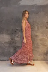 Vestido largo de crochet con diseño de red, en tonos rojizos y blancos. Presenta un corte sin mangas y una falda con volados en la parte inferior.